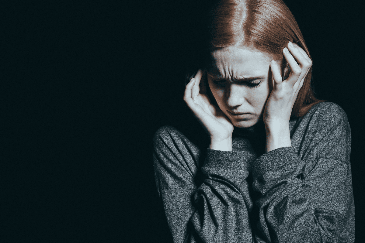 girl with red hair in distress covering her head