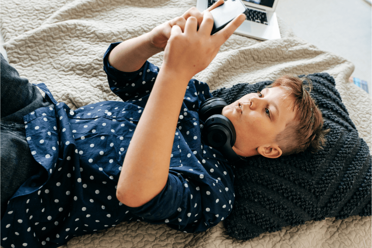 teenager lying down using their phone