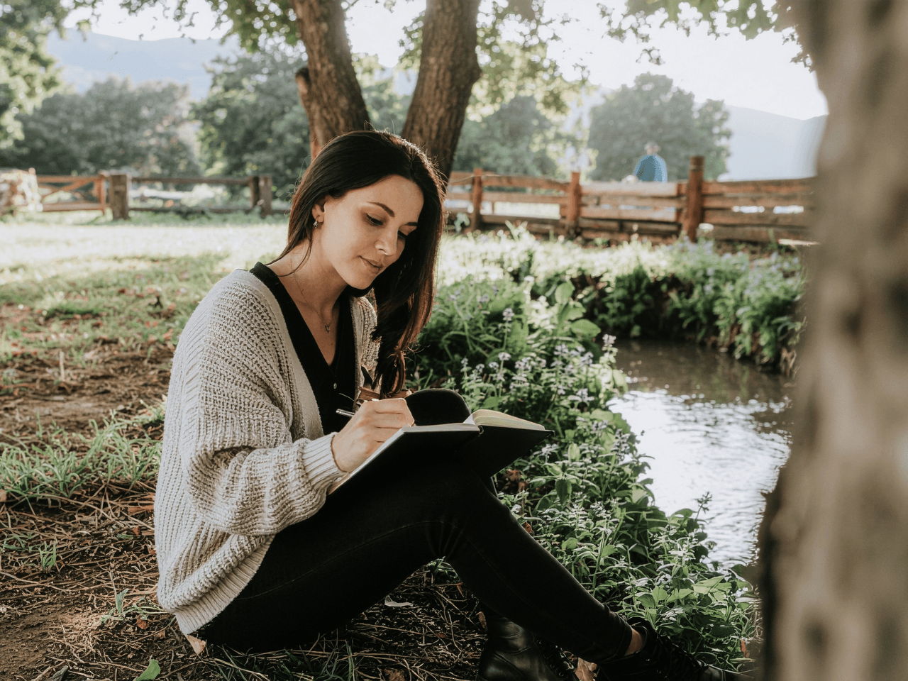 Woman sitting outside writing in journal
