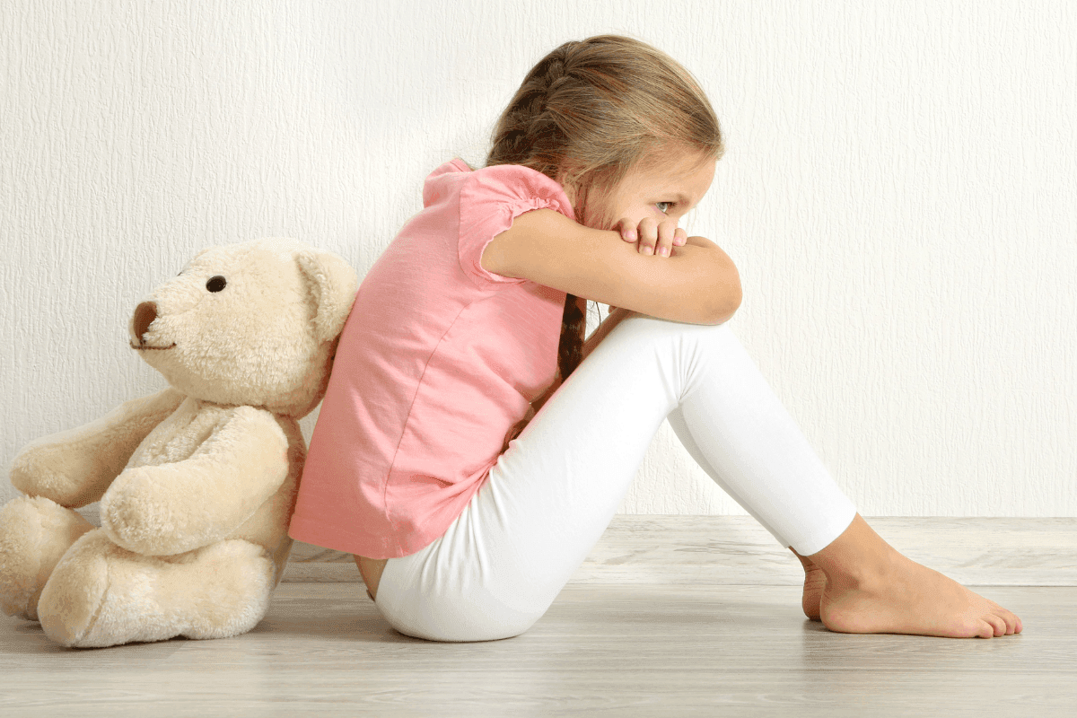 Young girl sitting on floor with teddy brear
