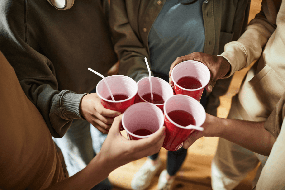 Teenagers holding cups with drinks at party